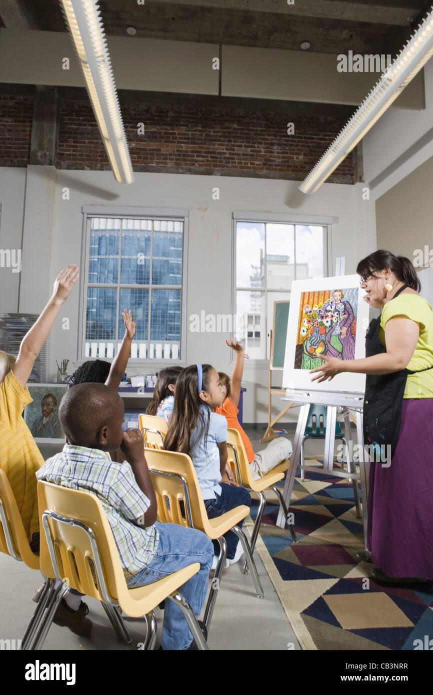 An art teacher standing by easel teaching her young students in art