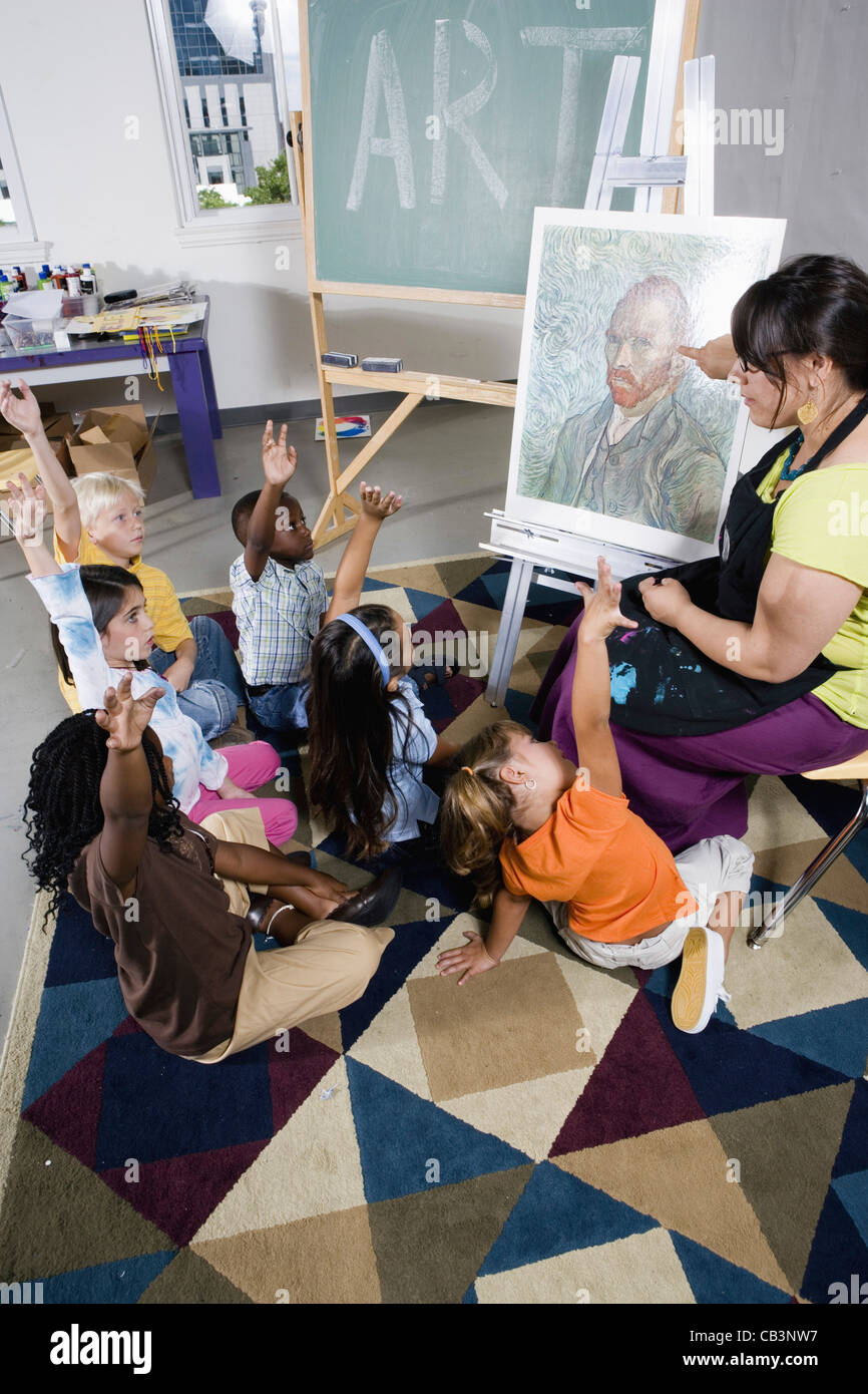 An art teacher by easel teaching her young students in art class Stock