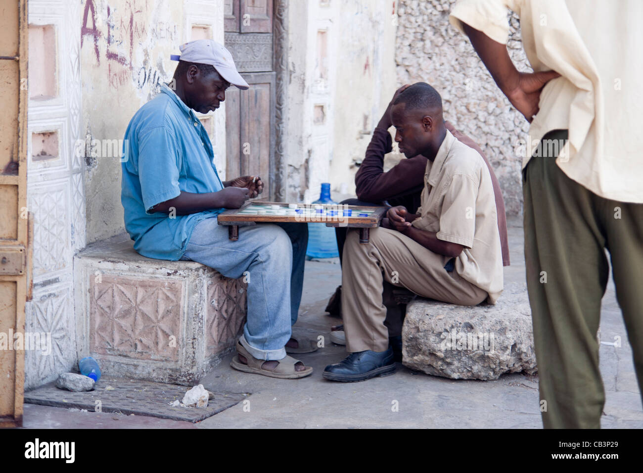 Men playing draughts board game in the back streets of Mombasa, Kenya