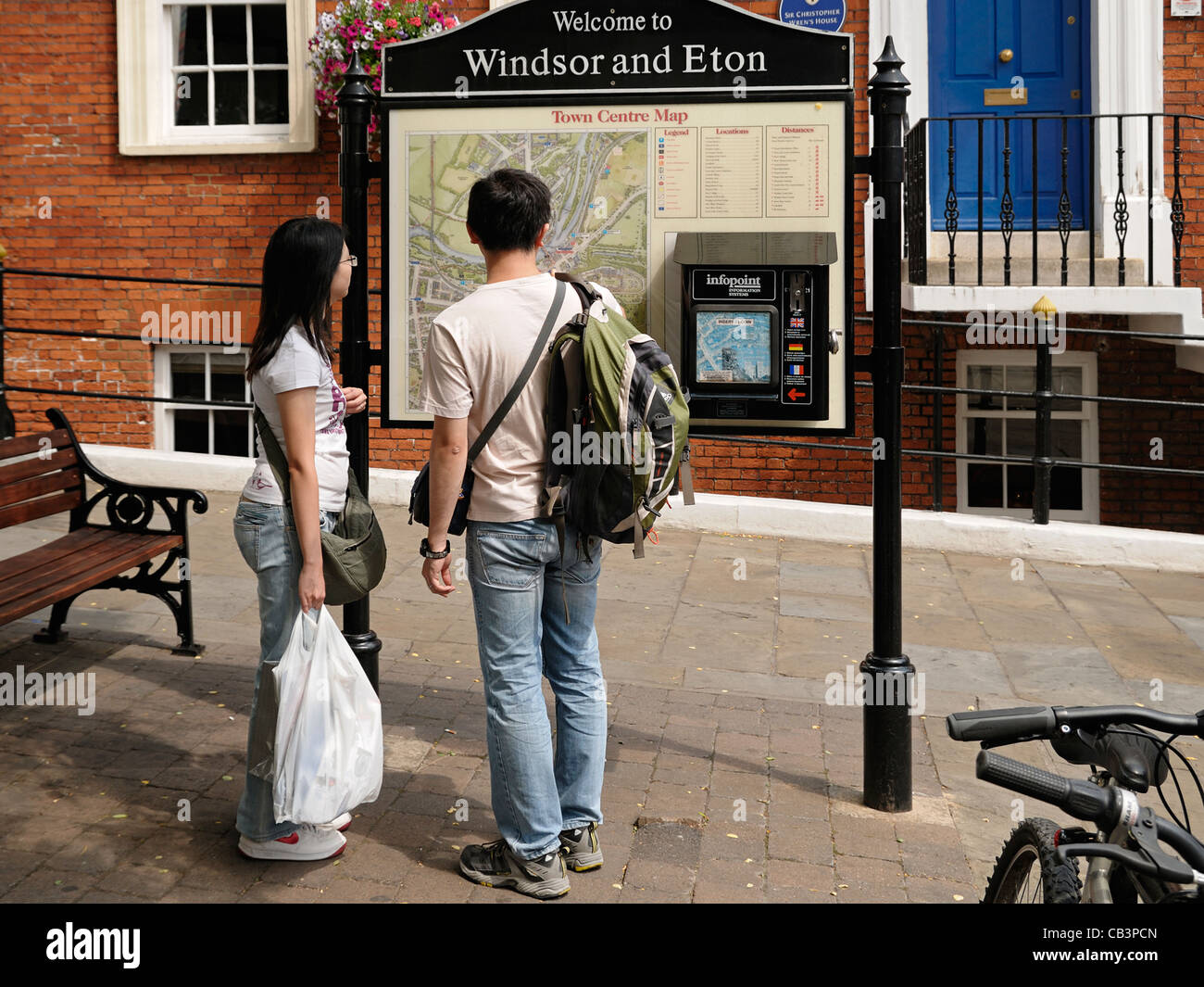 Couple Looking at a Street Tourist Information Point with a Map of Locations, Windsor and Eton, Berkshire, UK. Stock Photo