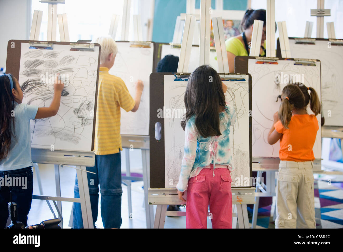 Boys and girls drawing on easels in art class Stock Photo Alamy