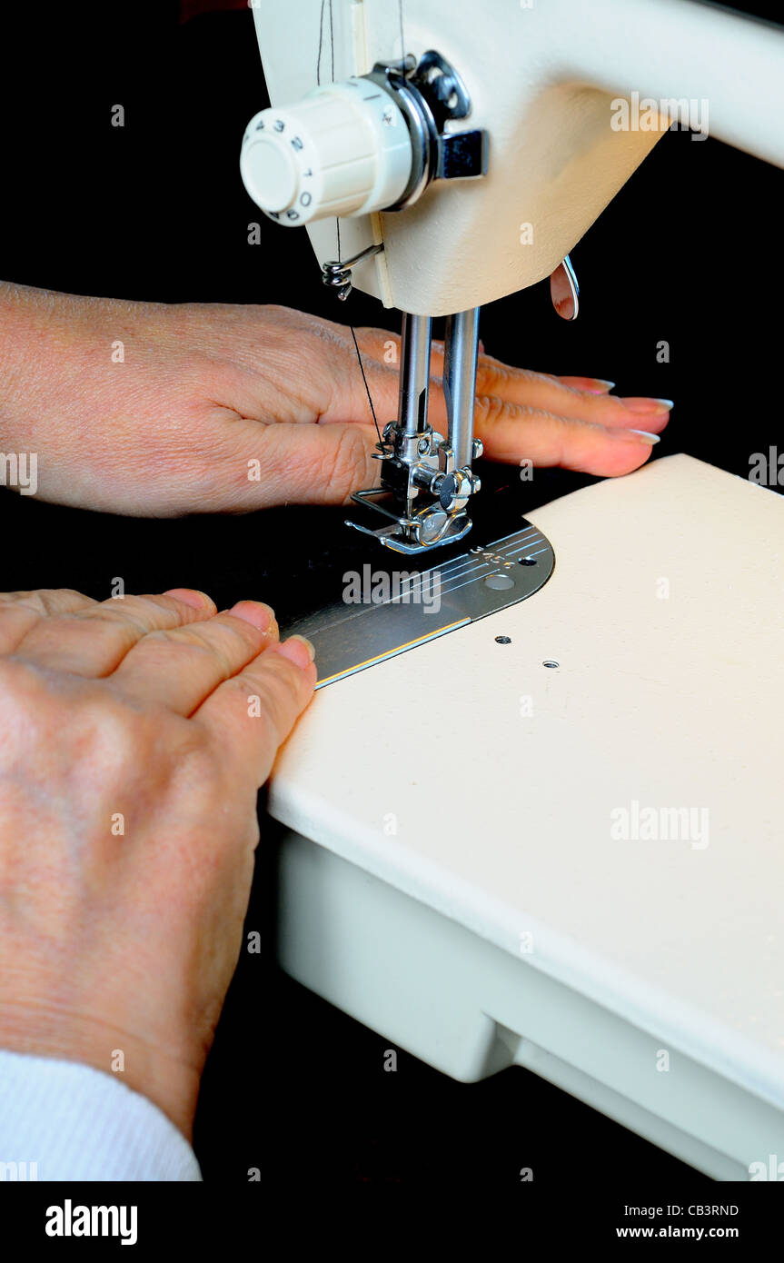 Woman using a domestic electric sewing machine to stitch black velvet, England, UK, Western Europe. Stock Photo