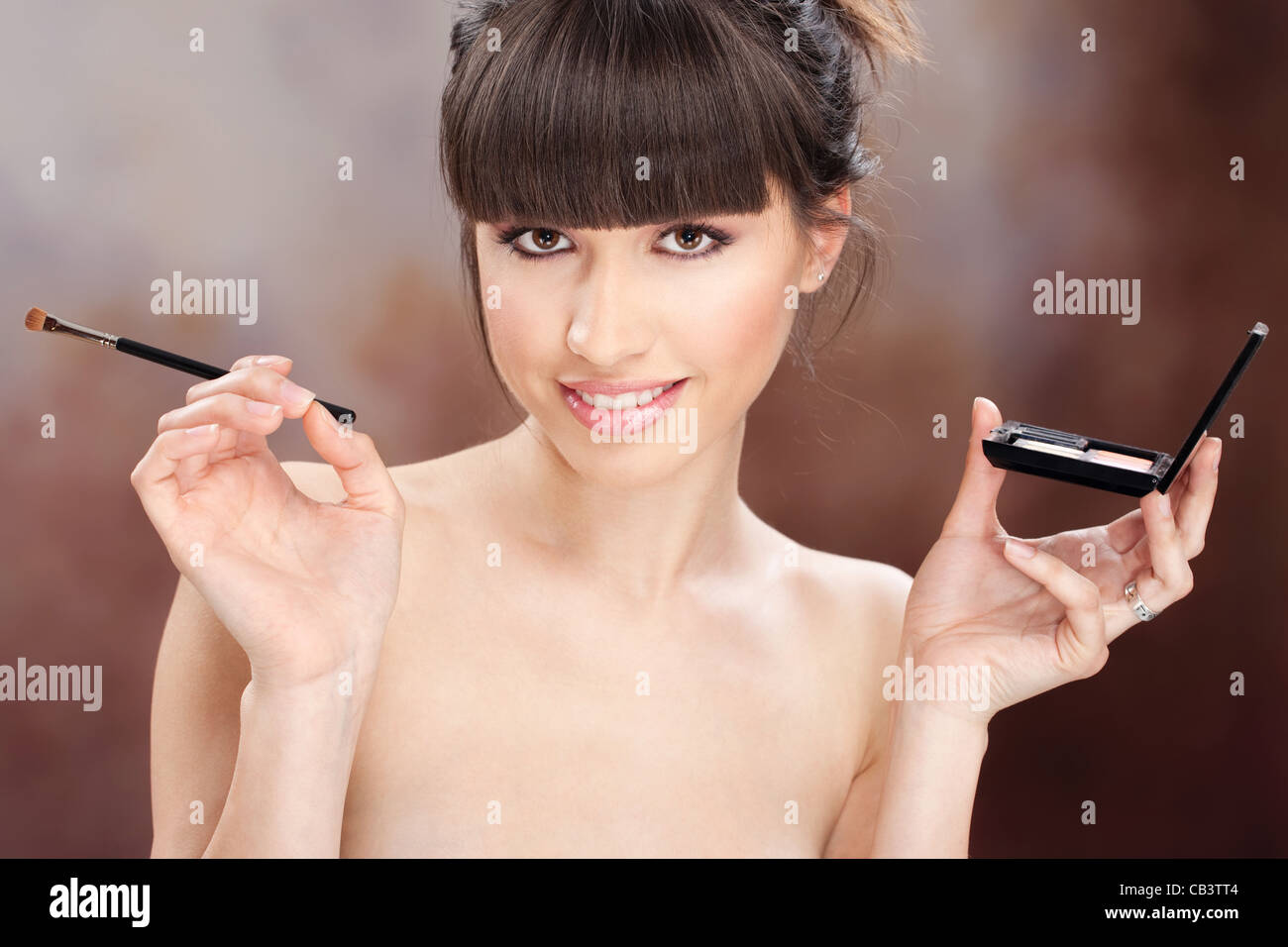 young pretty girl holding powder brush and makeup set Stock Photo