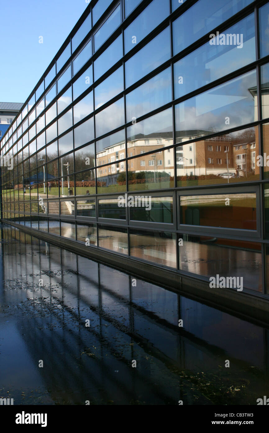 Glass fronted building reflecting other  buildings also reflected in water - Stock Photo