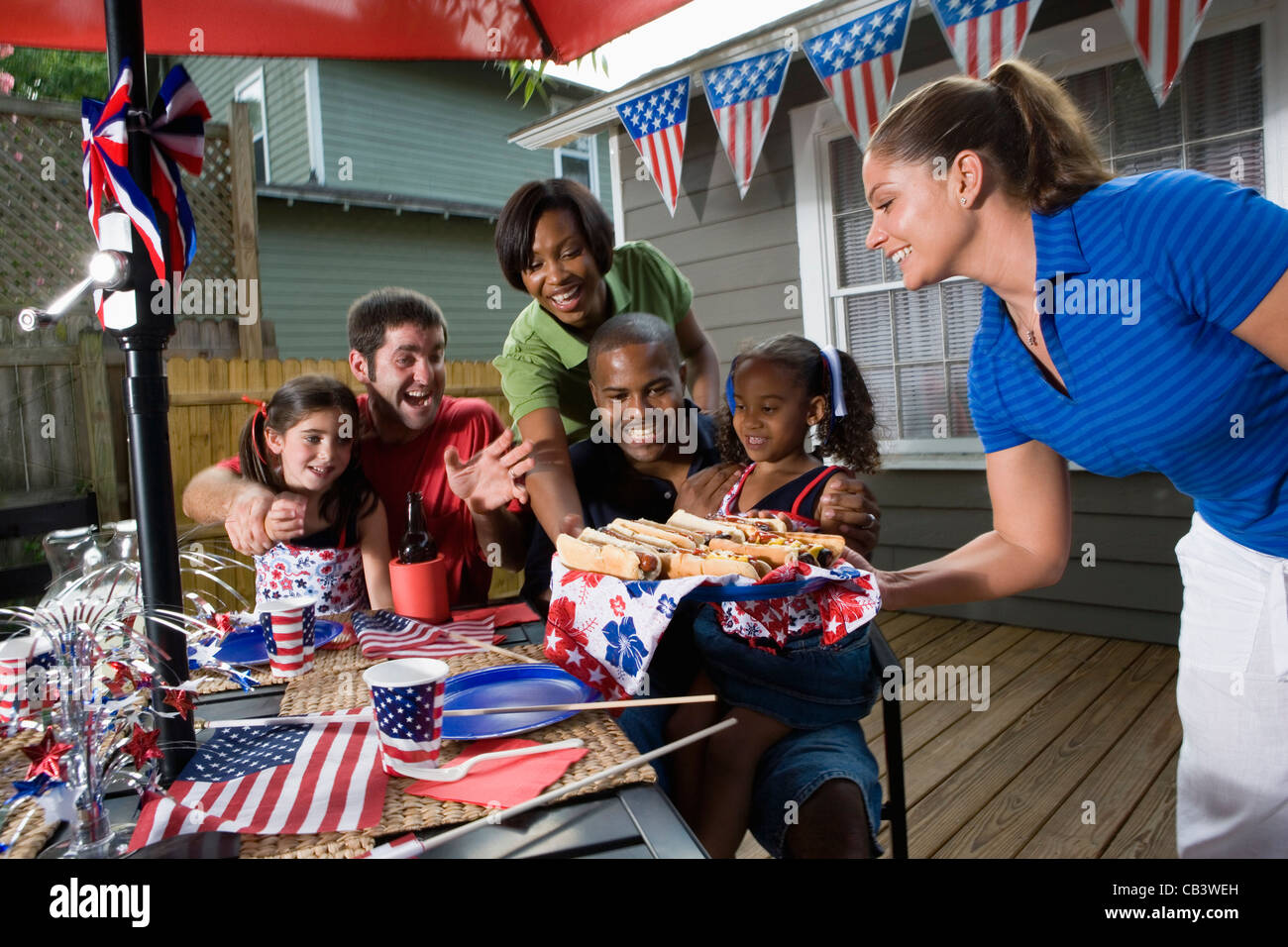 Two families on backyard patio enjoying a cookout on the 4th of July