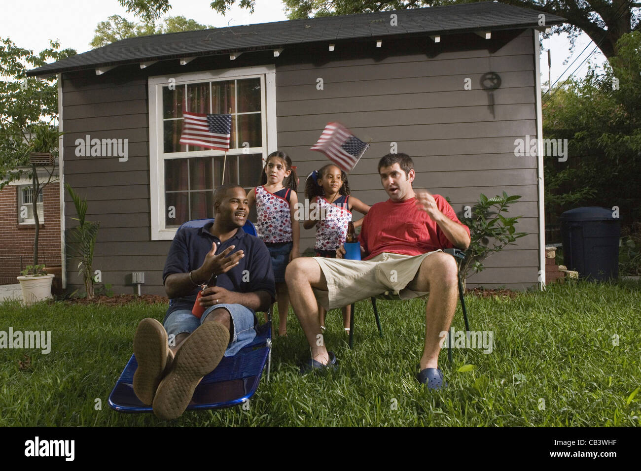Two young men sitting on lawn chairs enjoying a beer while daughters