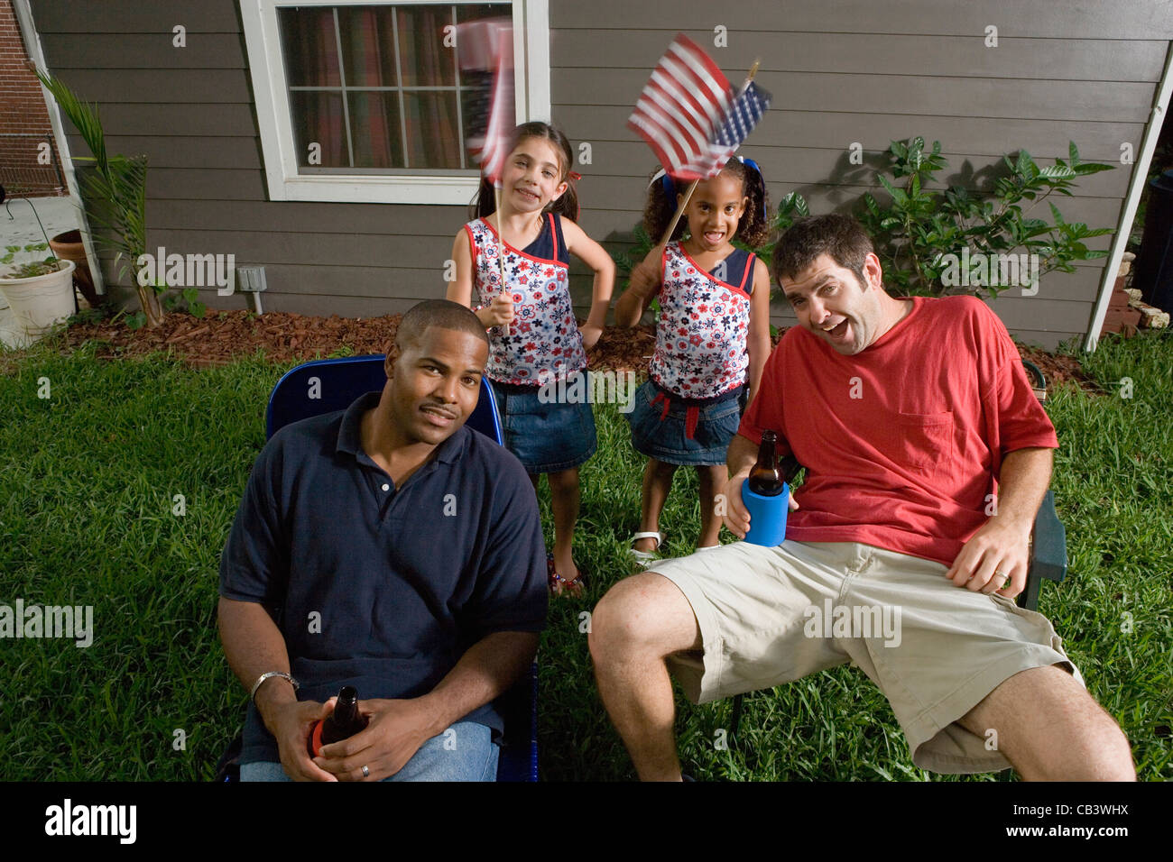 Two young men sitting on lawn chairs enjoying a beer while daughters