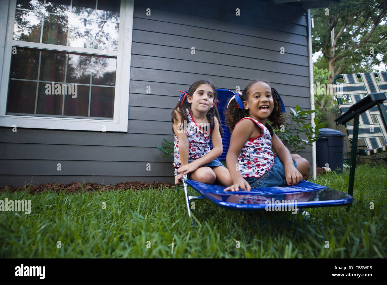 Two girls (6-7) sitting on lawn chair in backyard Stock Photo - Alamy