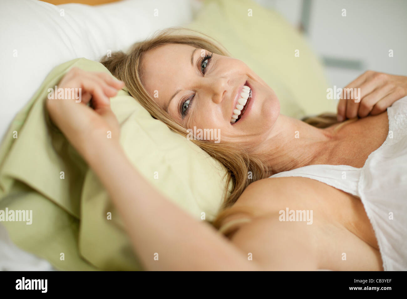 Portrait of a mature woman lying on the bed and smiling Stock Photo - Alamy