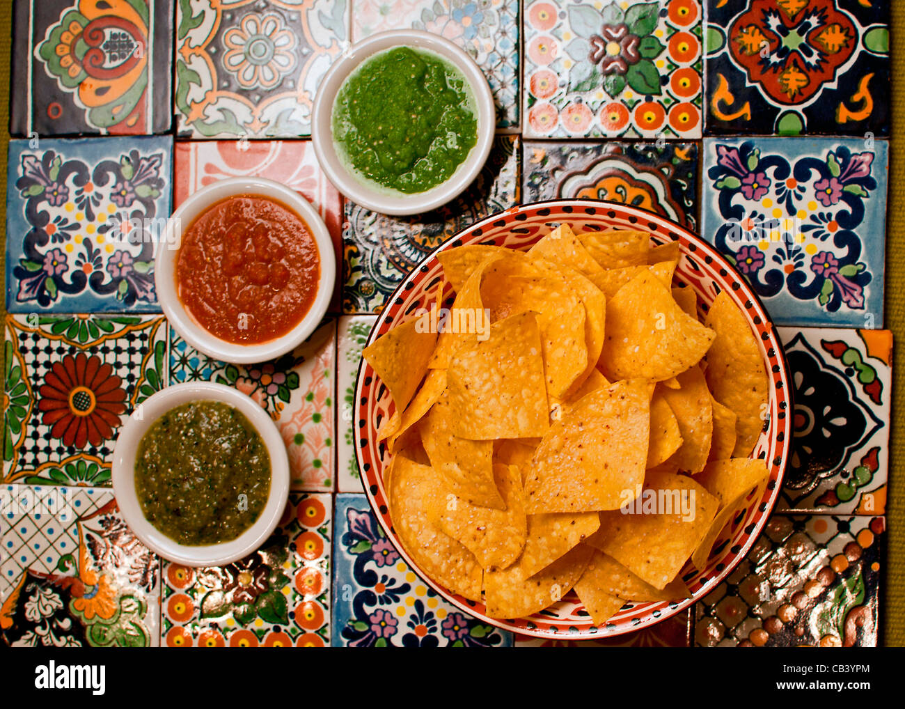 Close up of tortilla chips and salsa on colored tiles Stock Photo