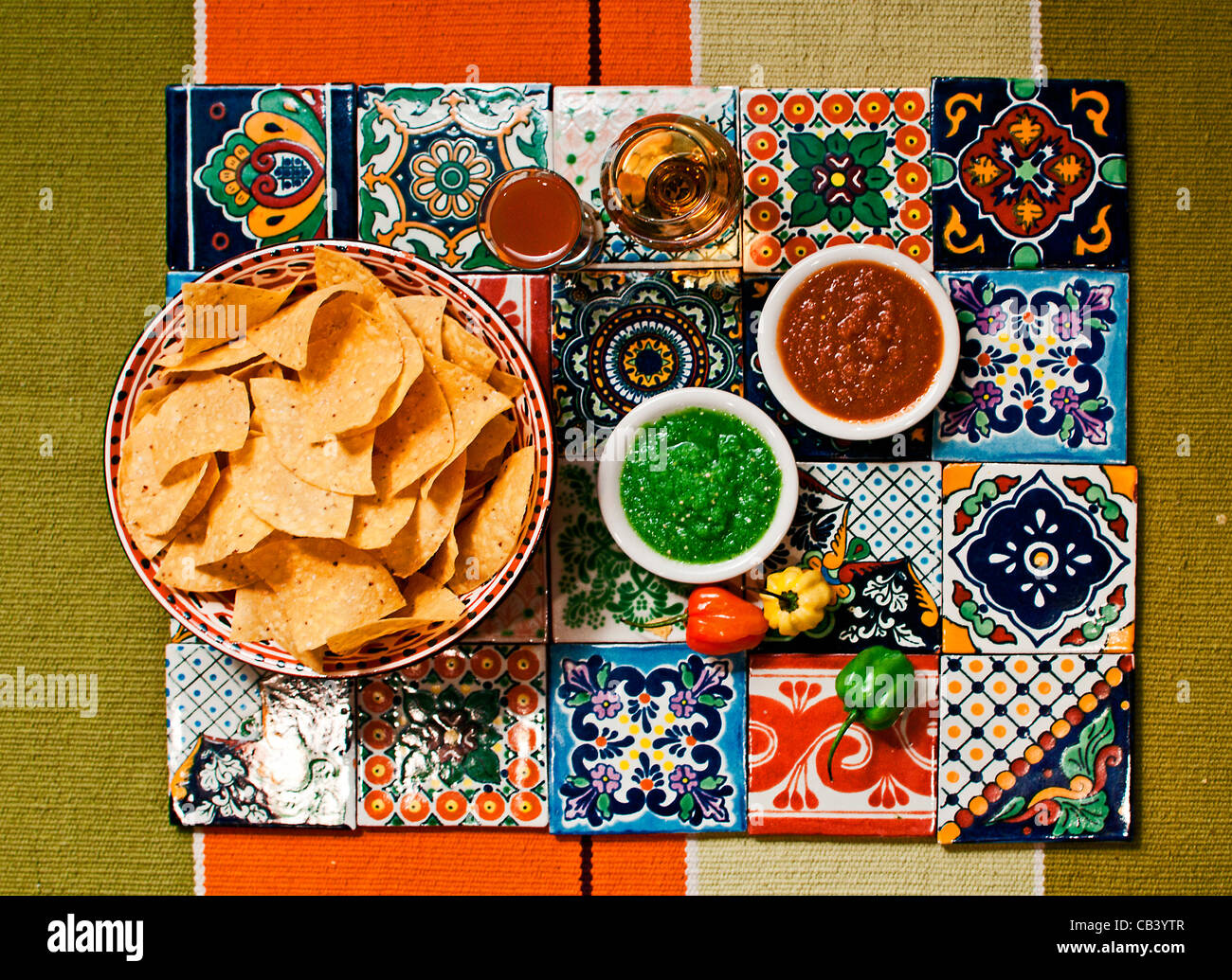 Close up of tortilla chips and salsa on colored tiles Stock Photo