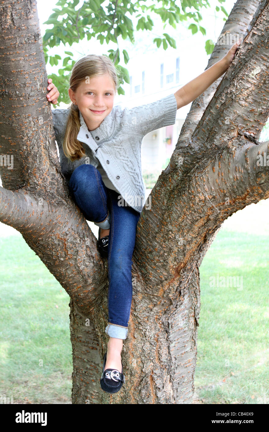 Girl sitting on a tree in a park Stock Photo - Alamy