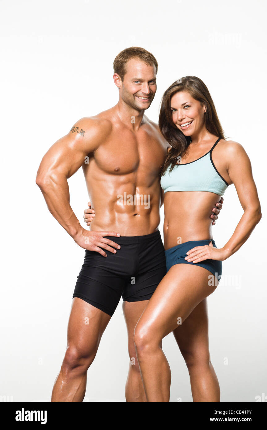 Male and female fitness models smiling to with arms around each