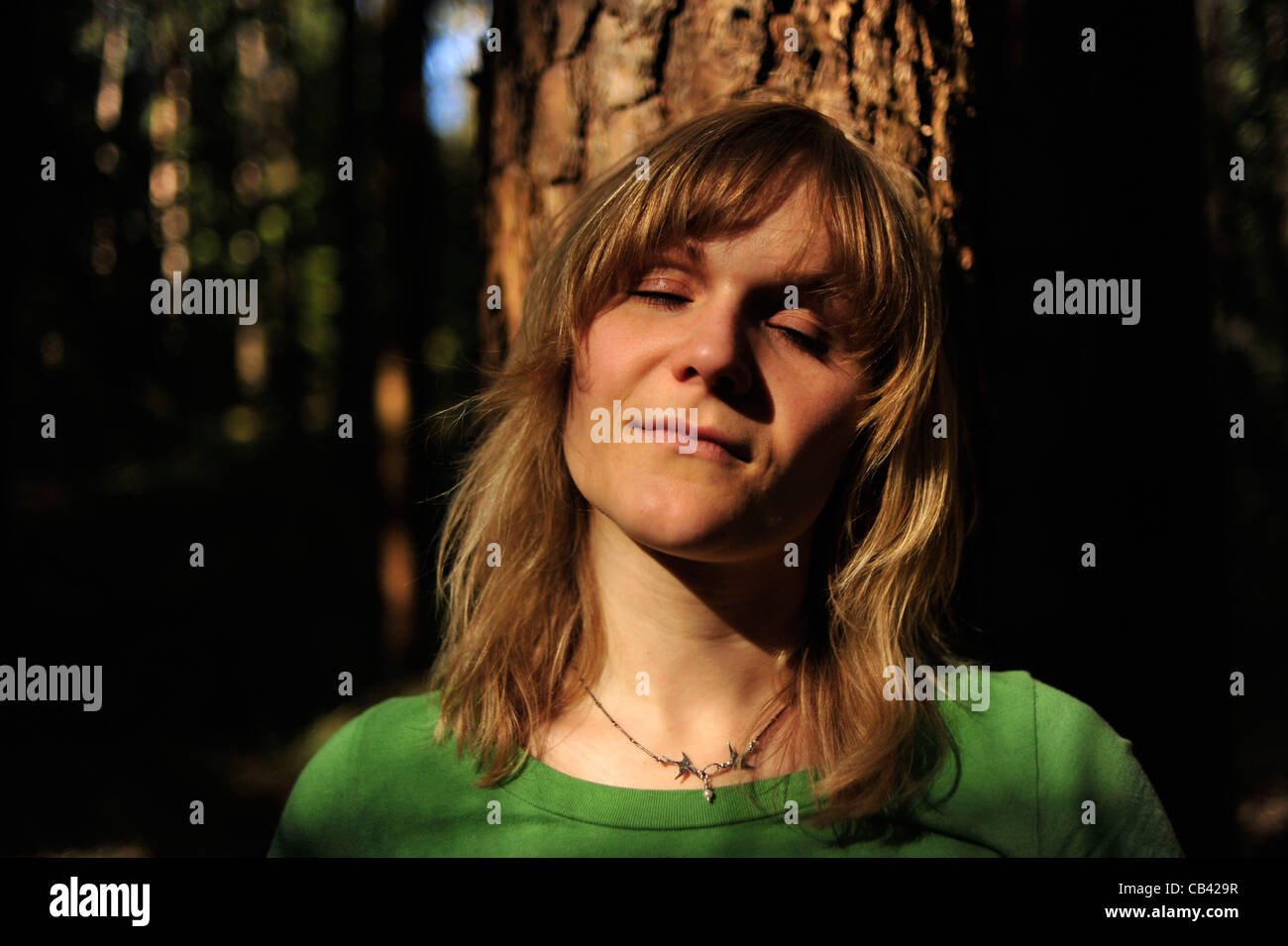 Woman with eyes closed relaxing in forest Stock Photo - Alamy