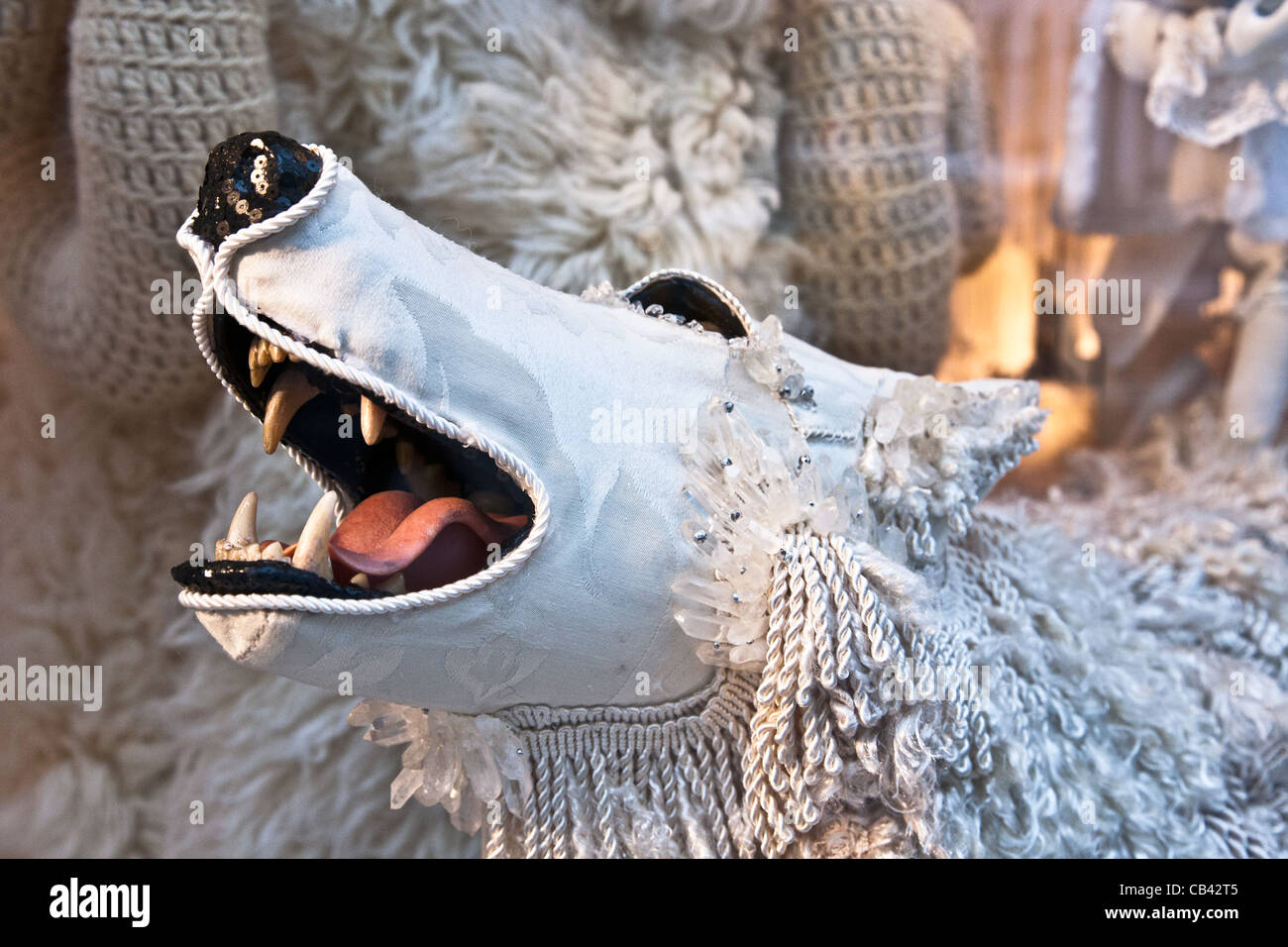 muzzle of wolf with big teeth & pink tongue peers from under white jeweled sheeps clothing in Bergdorf Goodman window New York Stock Photo