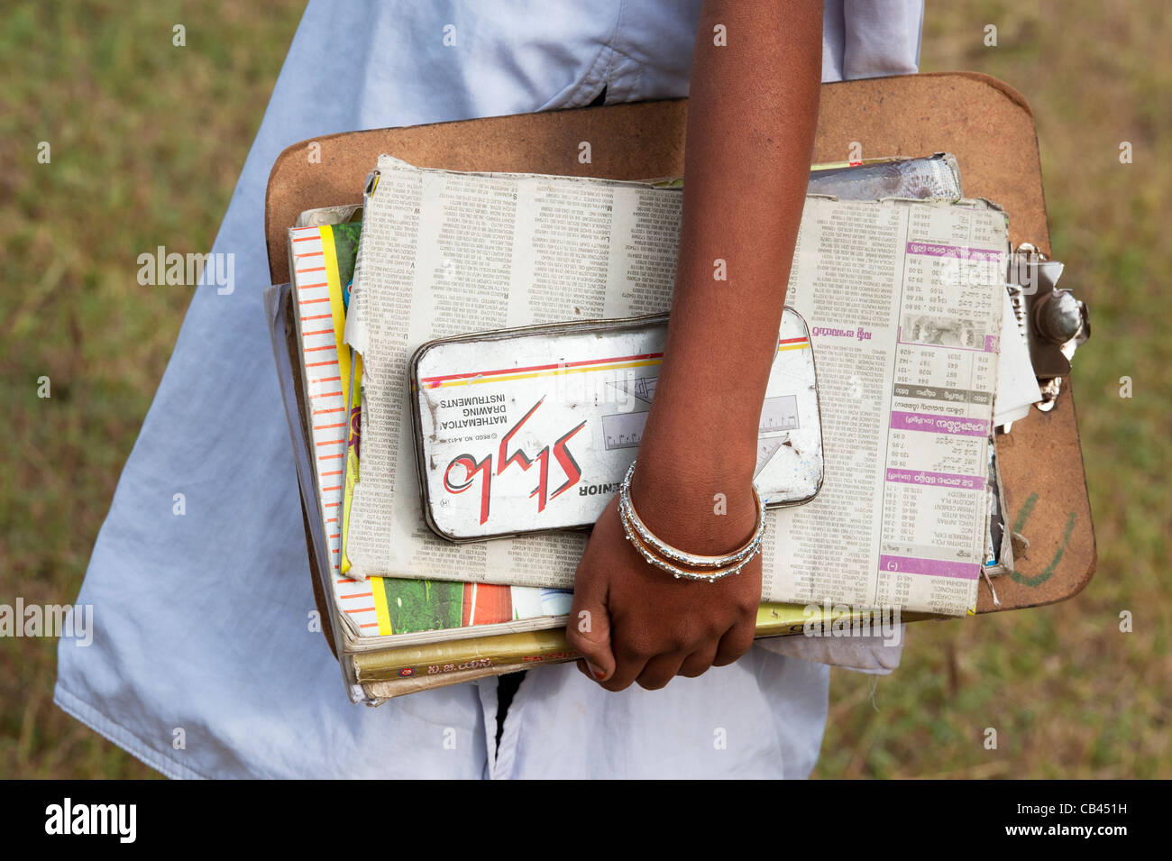Indian school girl carrying clipboard, writing books and pencil case whilst walking to school. Andhra Pradesh, India Stock Photo