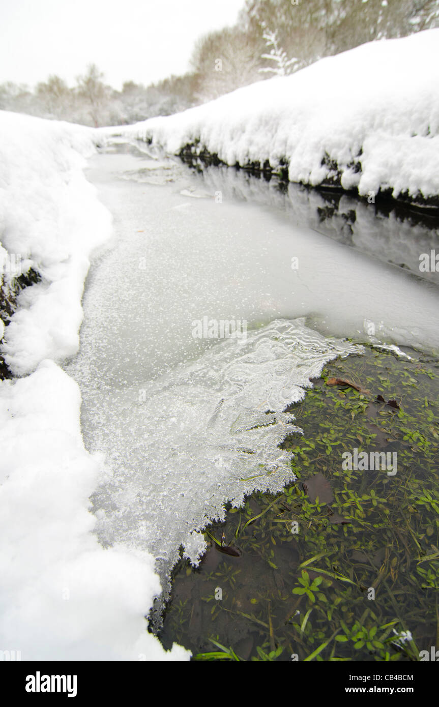 A frozen stream meanders its way through a snow covered golf course Stock Photo