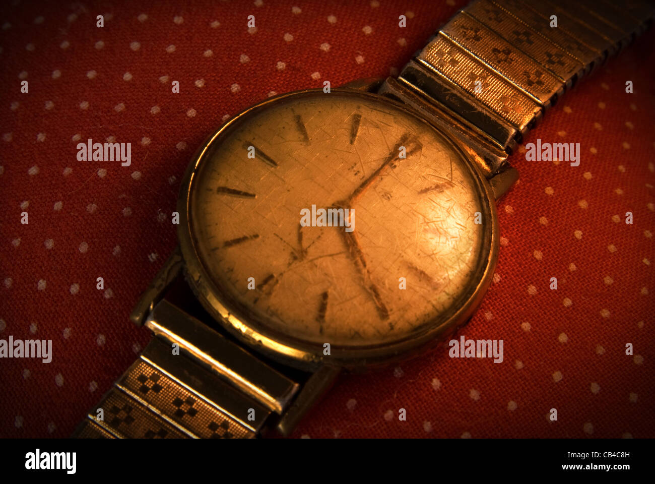 Retro golden wristwatch close up on red vintage cloth background. Stock Photo