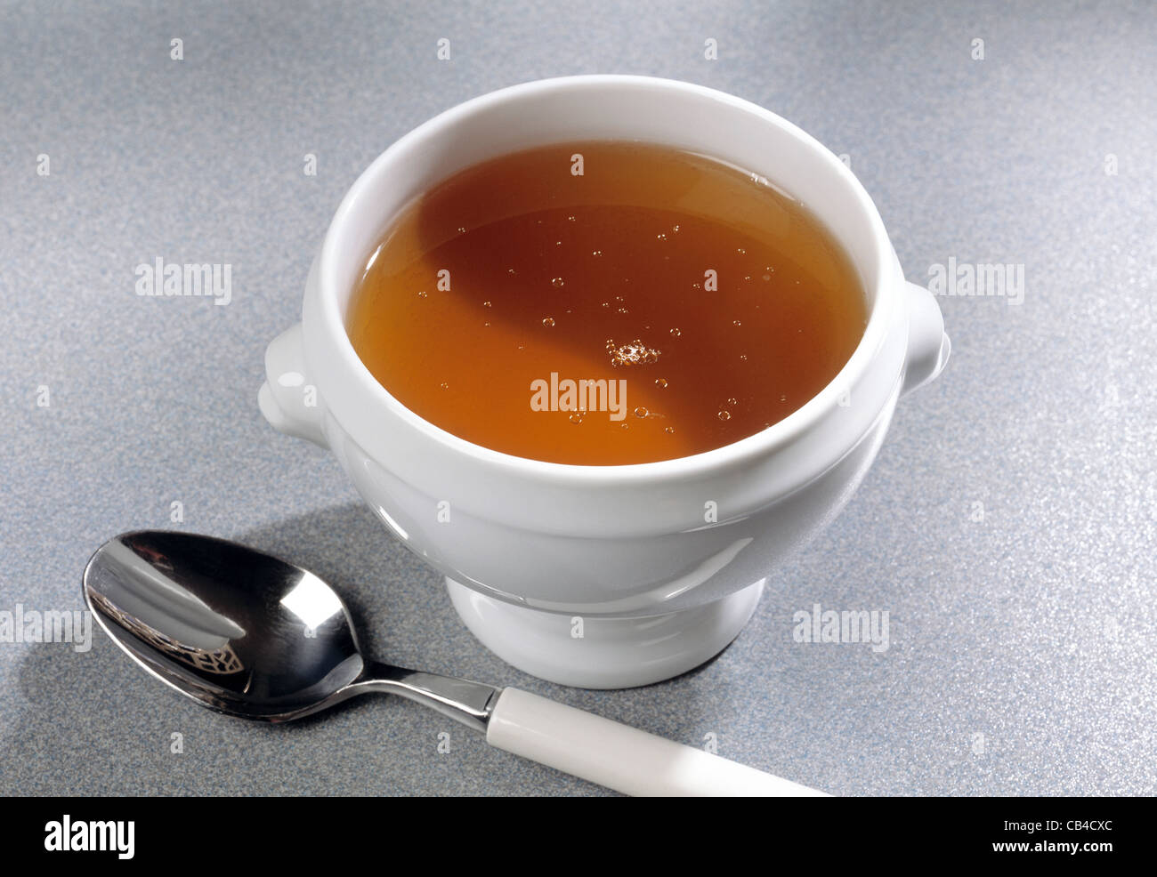 Broth consommé in white china bowl with spoon Stock Photo Alamy