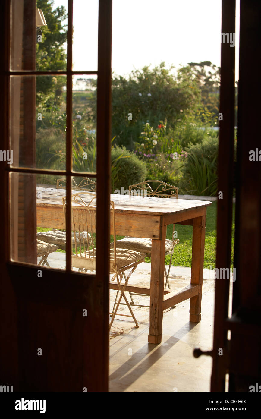 View through a door to a sunny terrace with table and chairs Stock Photo