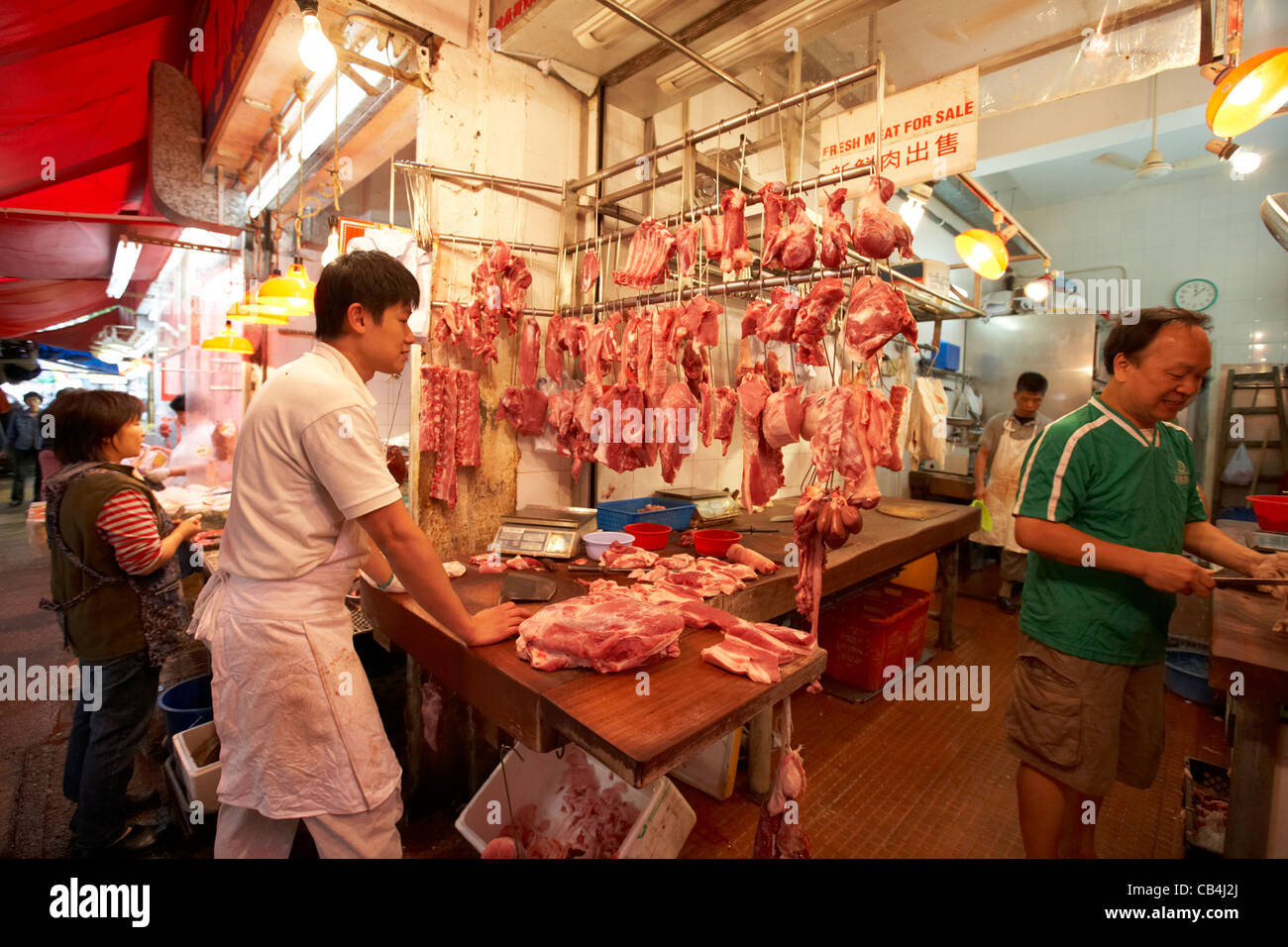 fresh pork meat hanging in a butchers stall at a food market in Stock