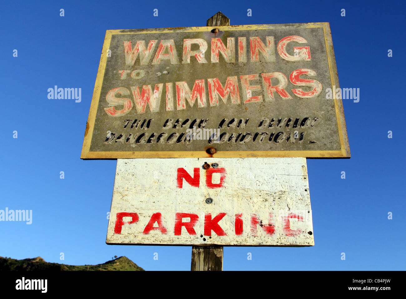 Old signpost warning about the dangers of swimming on West Coast beach. King Country. Stock Photo