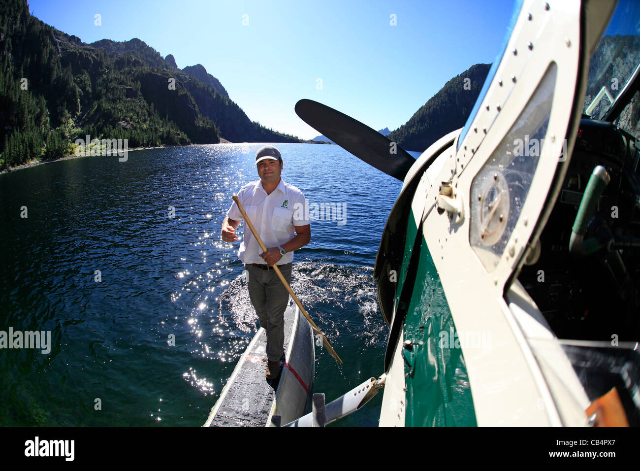 A floatplane pilot peddles his DeHavilland Beaver to the shore of a mountain lake in Vancouver Island Stock Photo