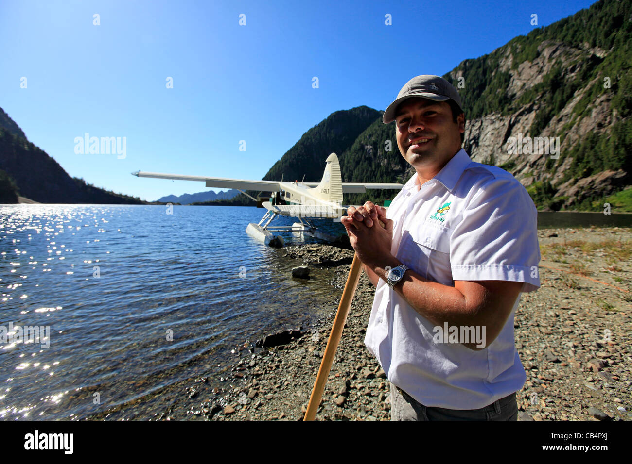 A pilot stands near his floatplane at a mountain lake in Vancouver Island Stock Photo