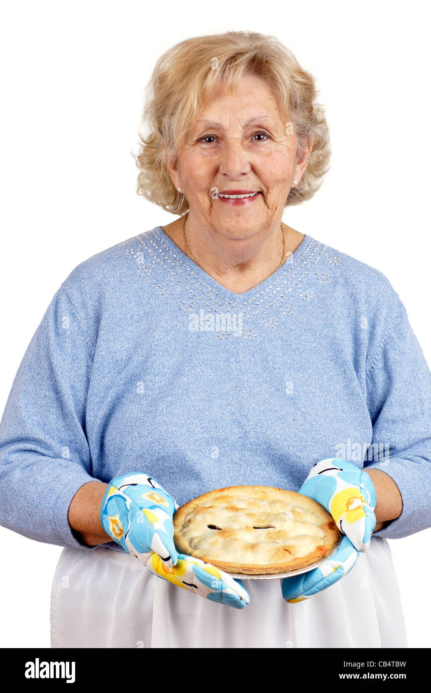 Welcome home concept: grandma is smiling while offering warm home cooked meat pie, wearing oven mitts. Stock Photo
