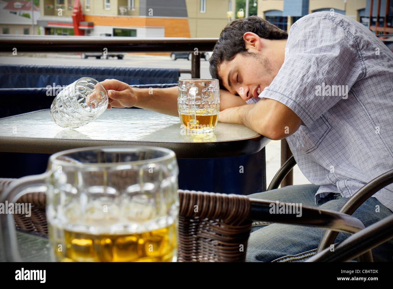 Young man asleep outdoors on pub's terrace after drinking too much beer