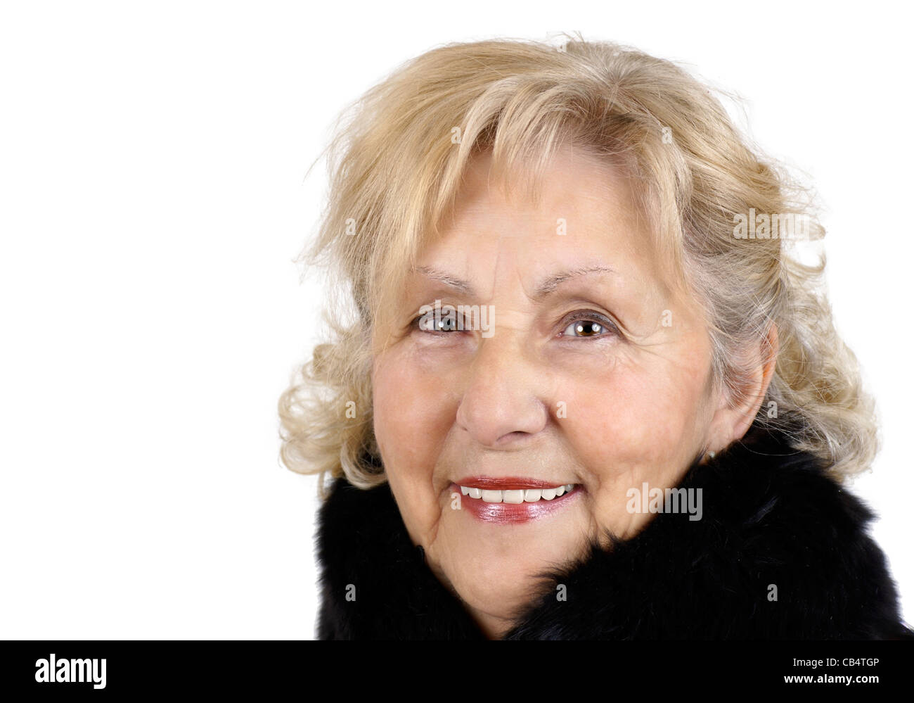 Portrait of a happy friendly senior woman smiling looking at camera and wearing a black fur collar for the cold winter day. Stock Photo