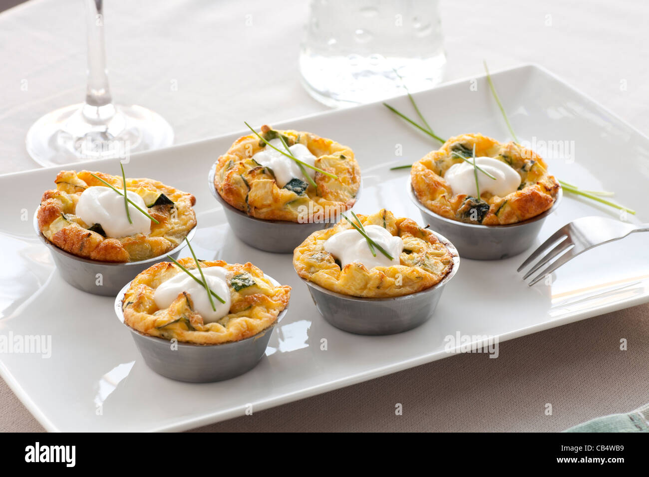 Five quiche appetizers with sour cream and chives. Stock Photo