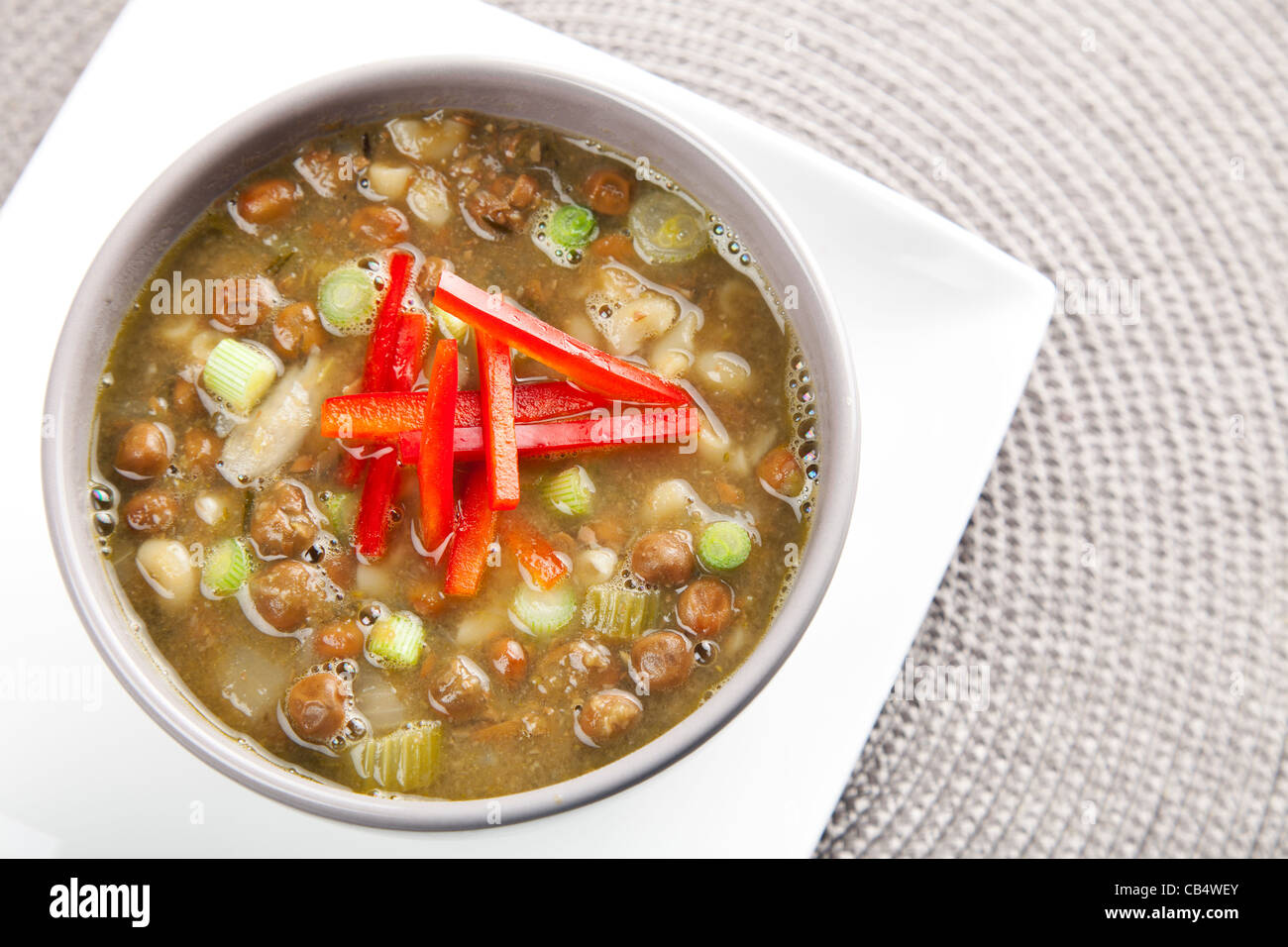 Bowl of fresh soup with kapucijners green onions and red bell pepper garnish Stock Photo
