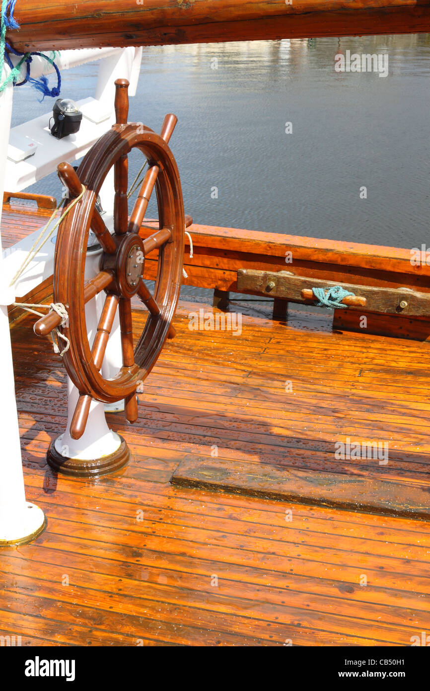 Ship's wheel on the deck of a traditional boat Stock Photo