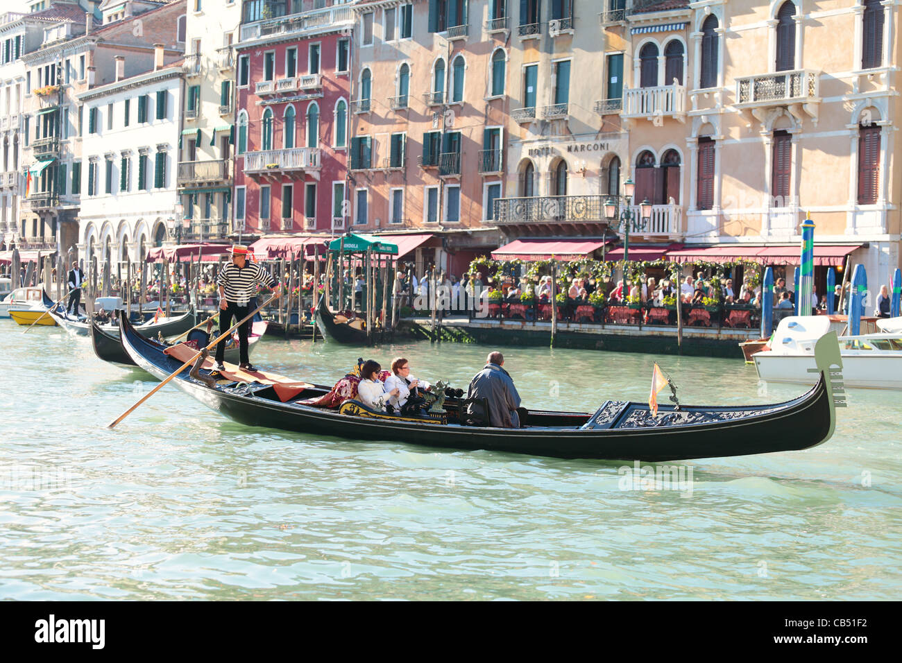A gondola on the Grand Canal, with shops and restaurants close to the Rialto Bridge. Stock Photo