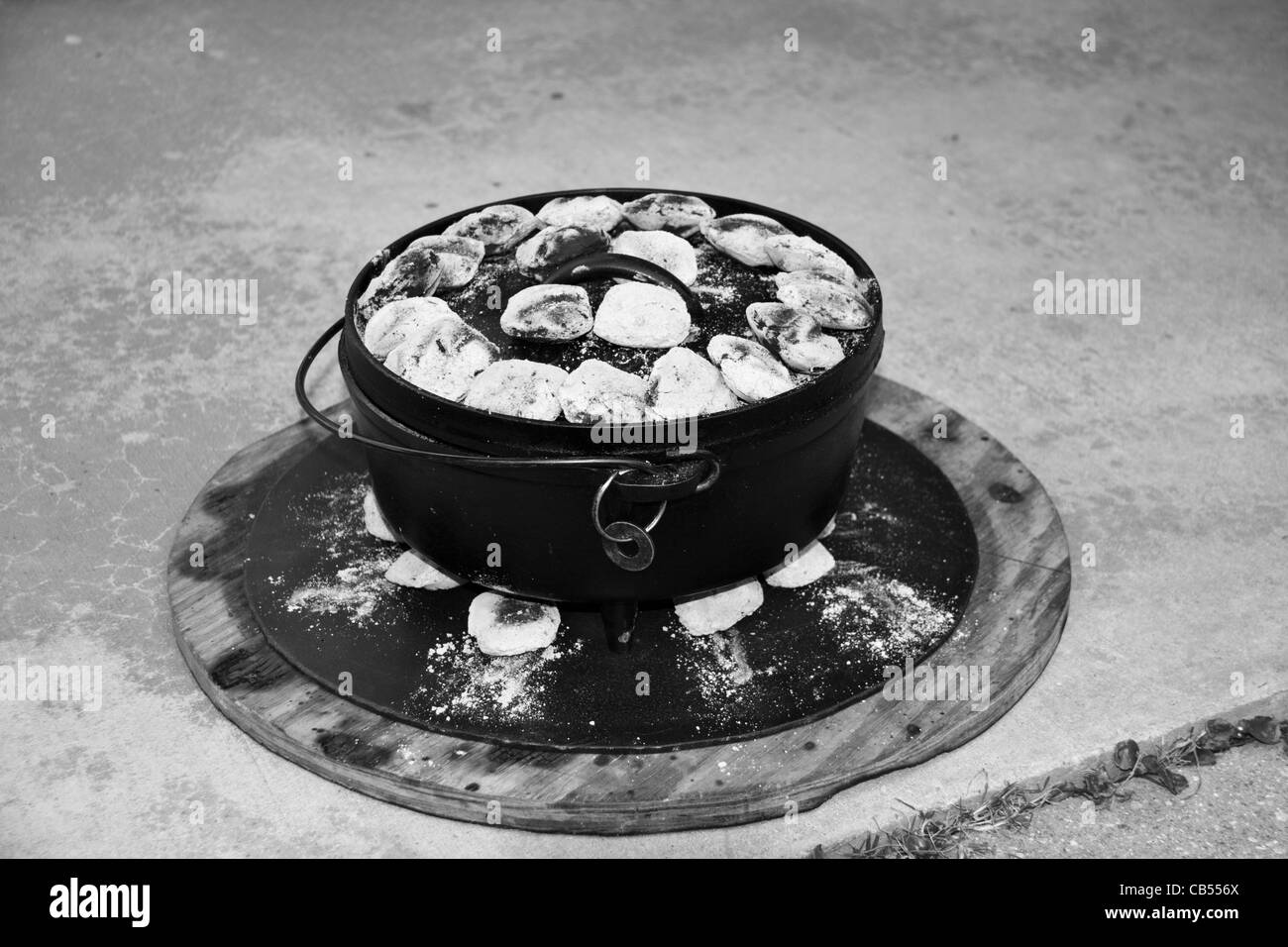 Dutch Oven outdoor cooking using cast iron pots with metal base support. Coals are placed above and below pot. Stock Photo