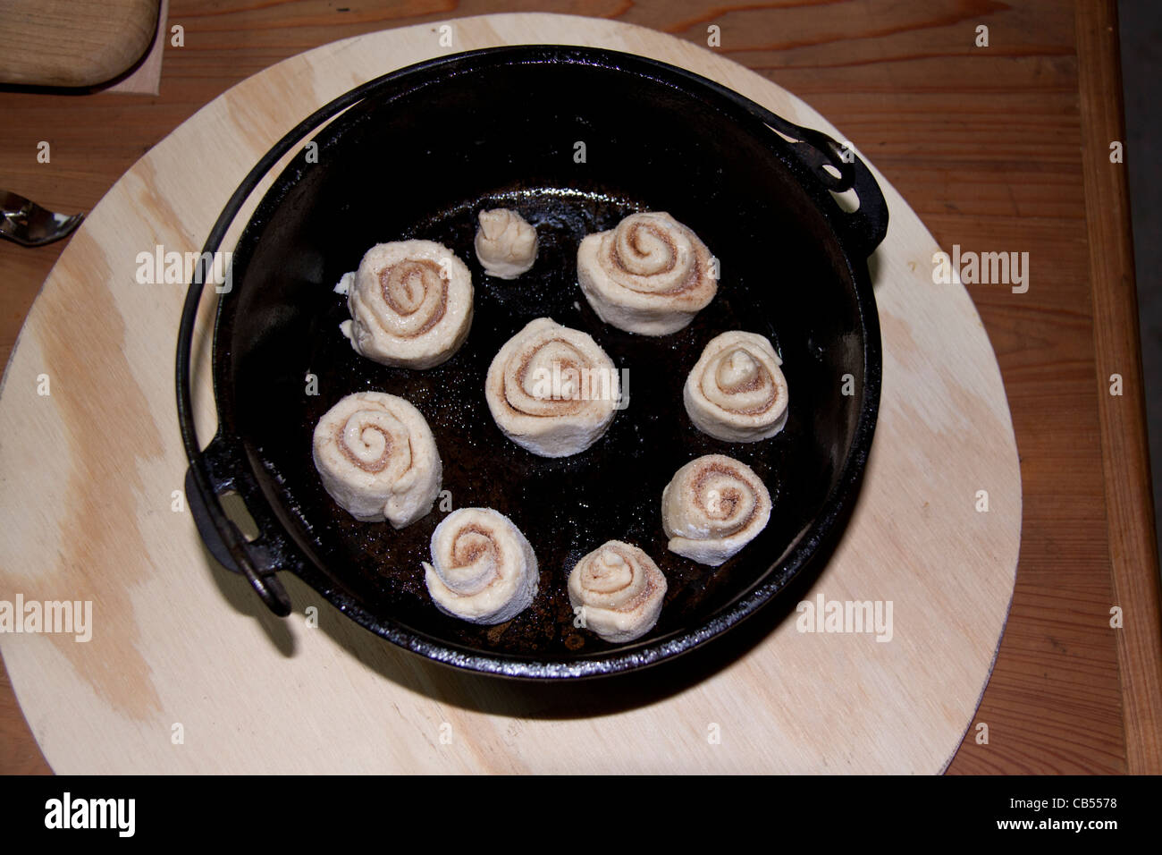 Cinnamon rolls ready to be cooked in cast iron 'black iron' Dutch Oven pot using hot coals. Stock Photo