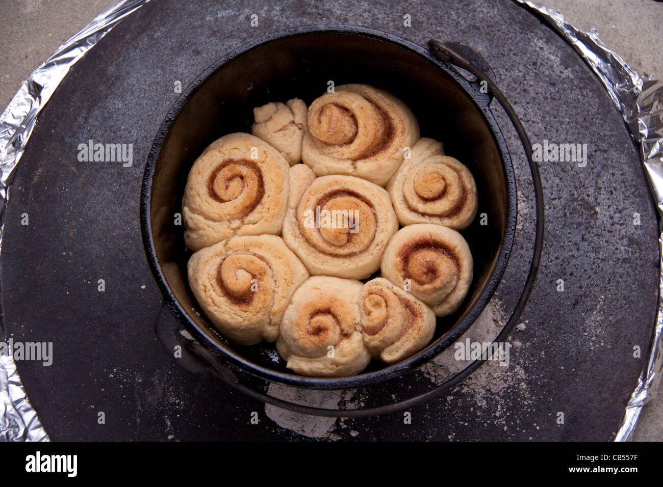 Cinnamon rolls cooked in cast iron 'black iron' Dutch Oven pot using hot coals. Stock Photo