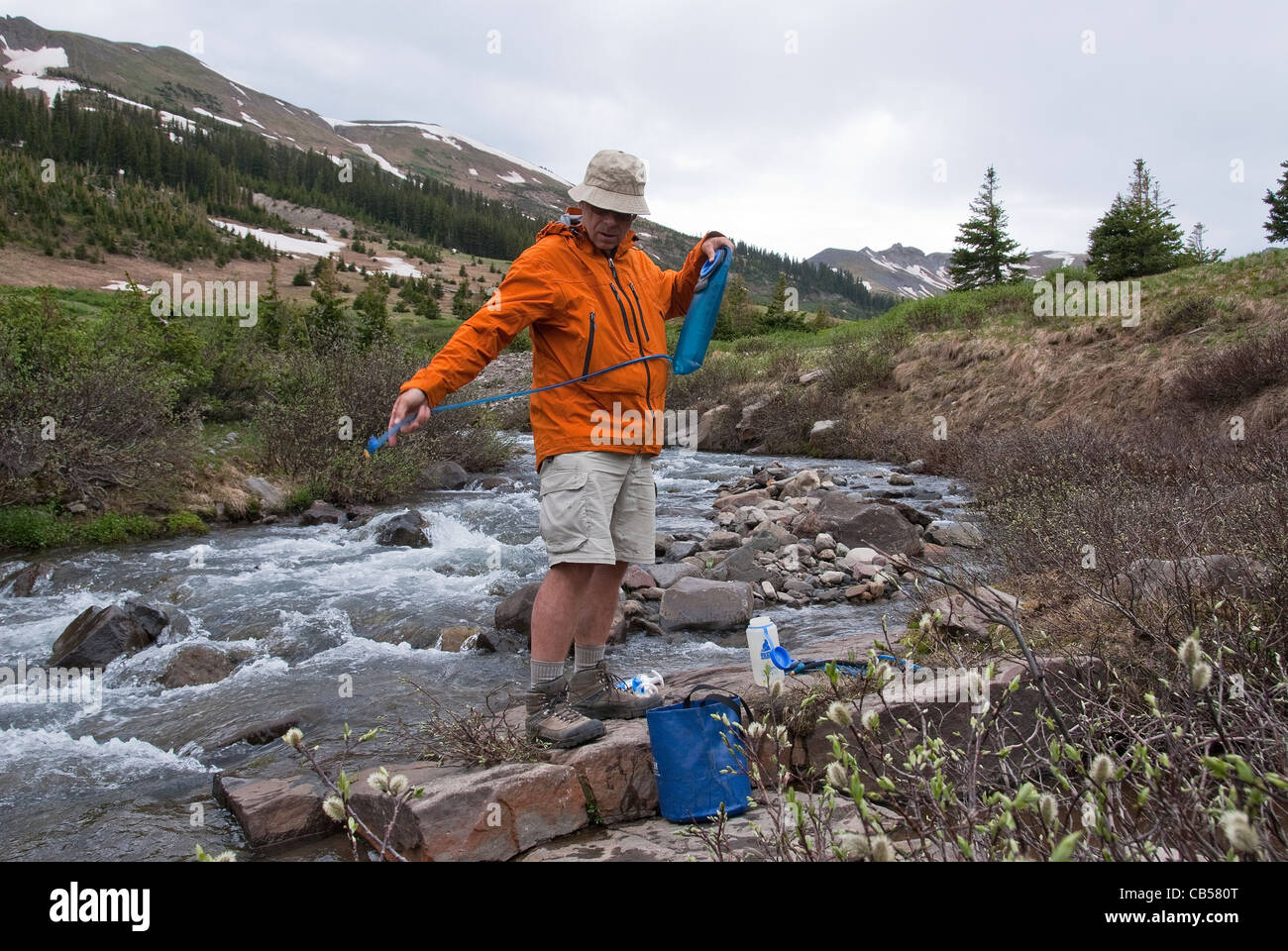 Mike Vining filtering water at Adams Fork of the Conejos South San Juan Wilderness Colorado USA Stock Photo