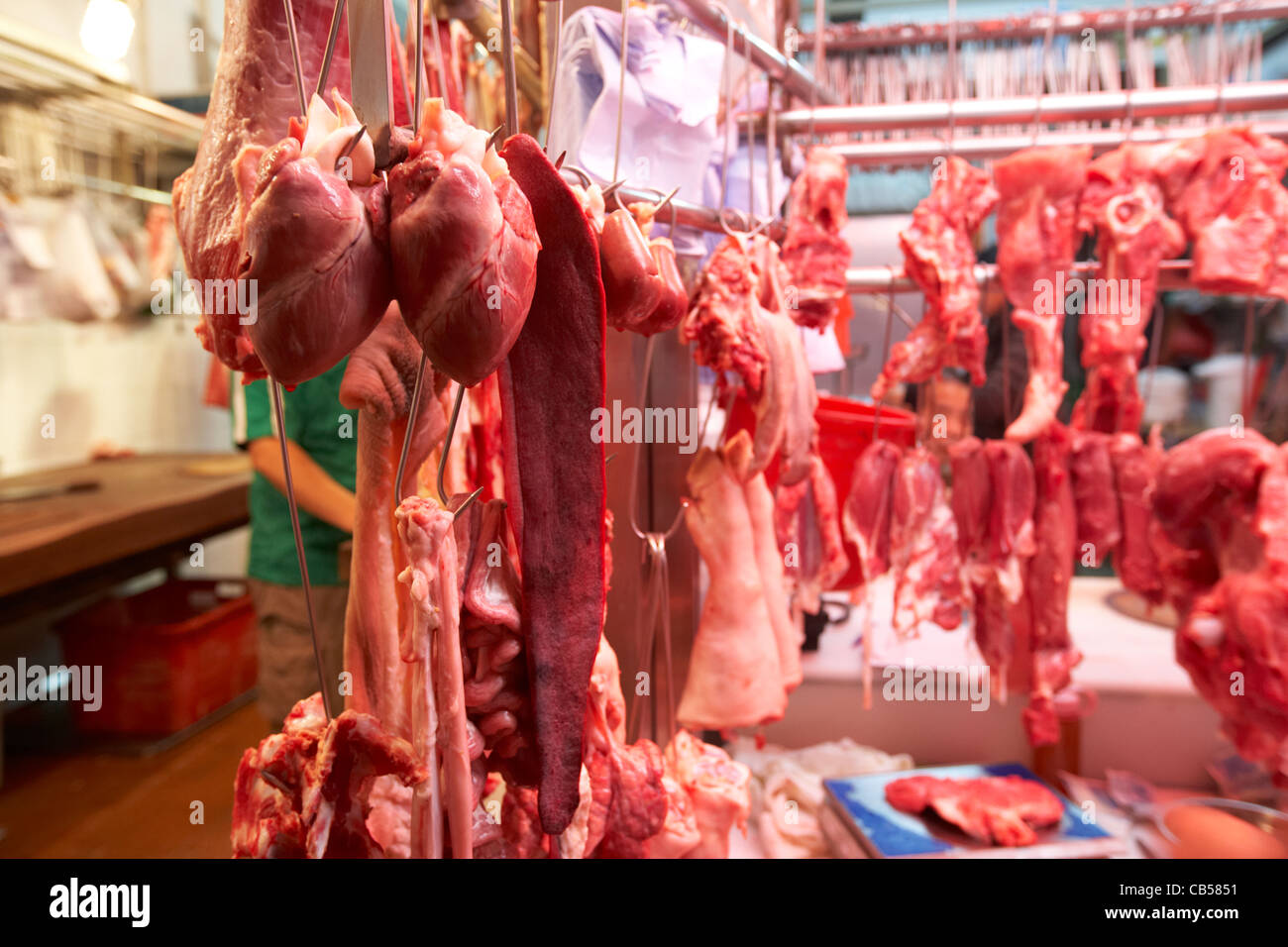 fresh meat and offal hanging in a butchers stall in an outdoor market in mong kok district kowloon hong kong hksar china Stock Photo