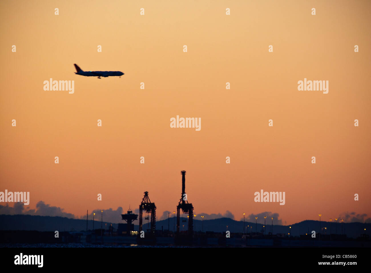 Airplane approaches  Brisbane Airport over the Port of Brisbane at dawn. Viewed from Shorncliffe Jetty Stock Photo