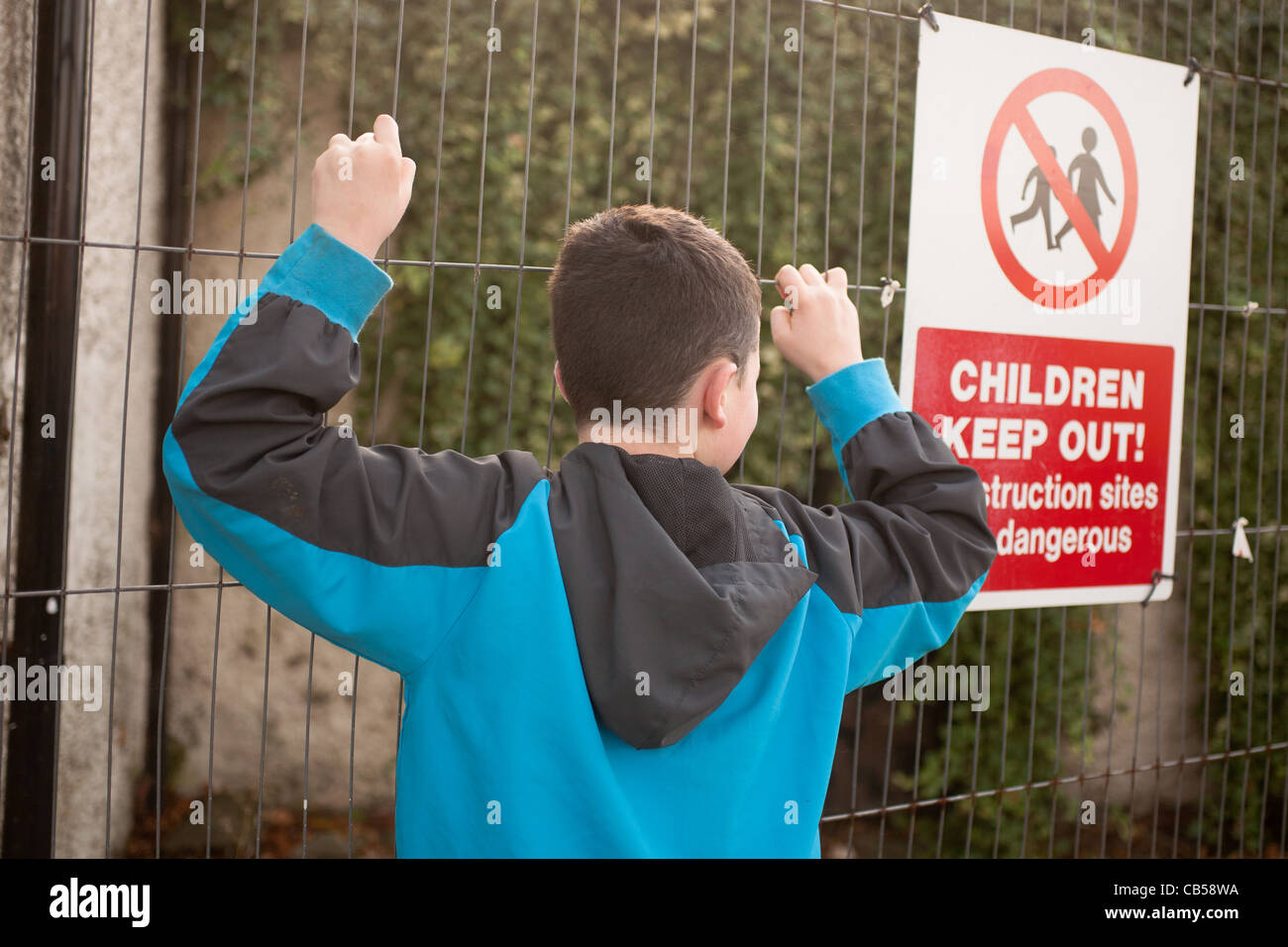 A young boy climbing a fence Stock Photo