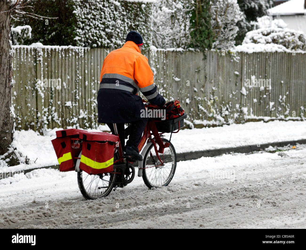 Postman Riding a Bicycle In The Snow Surrey England Stock Photo