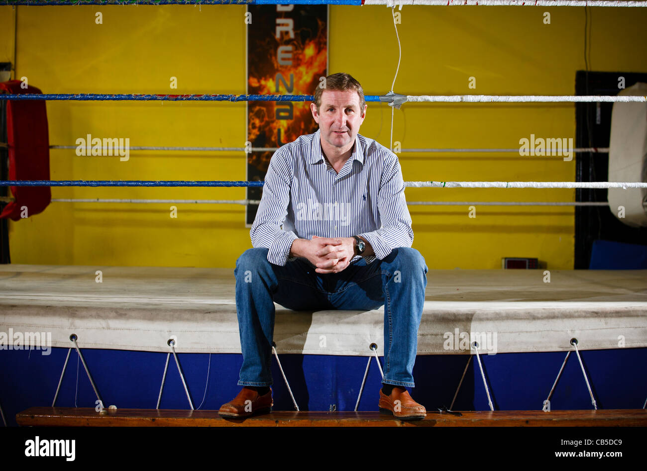 Boxing promoter sat on the side of a boxing ring Stock Photo