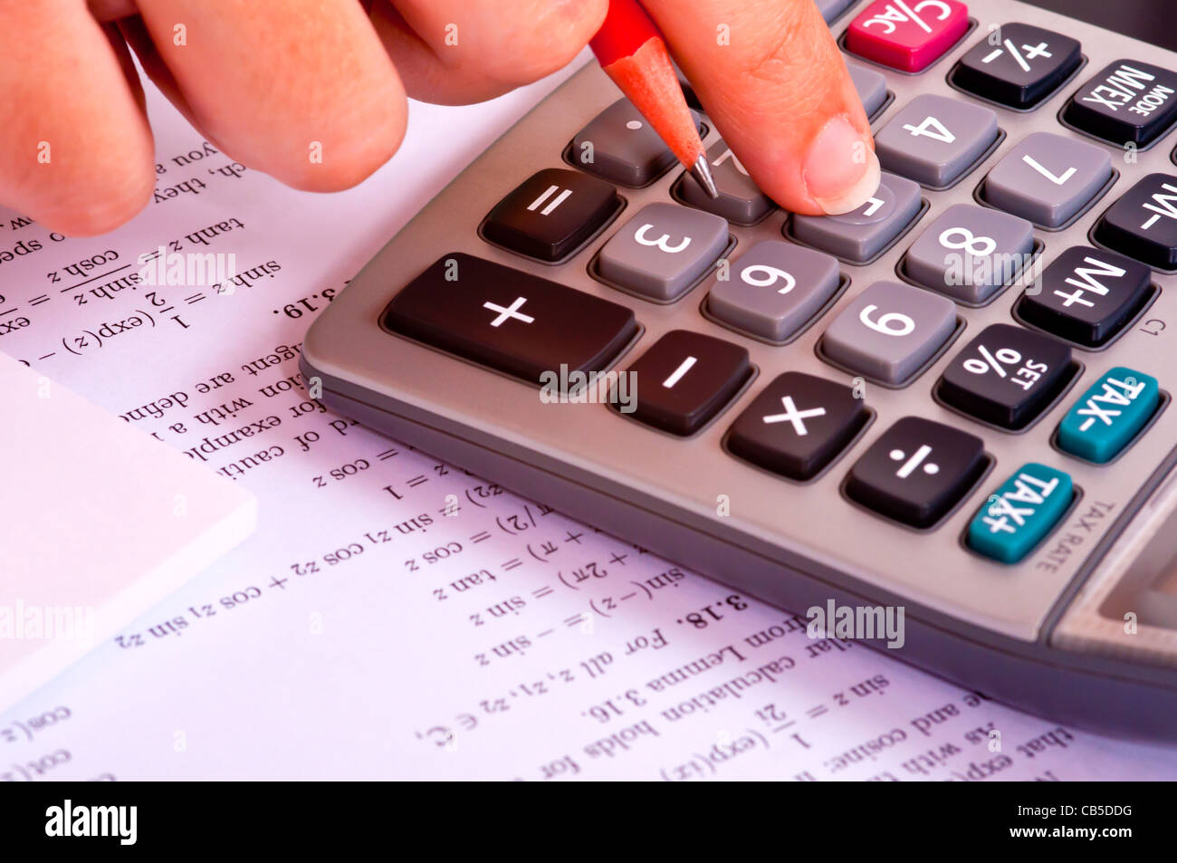 Student doing maths exercises with a calculator and a red pencil. Stock Photo