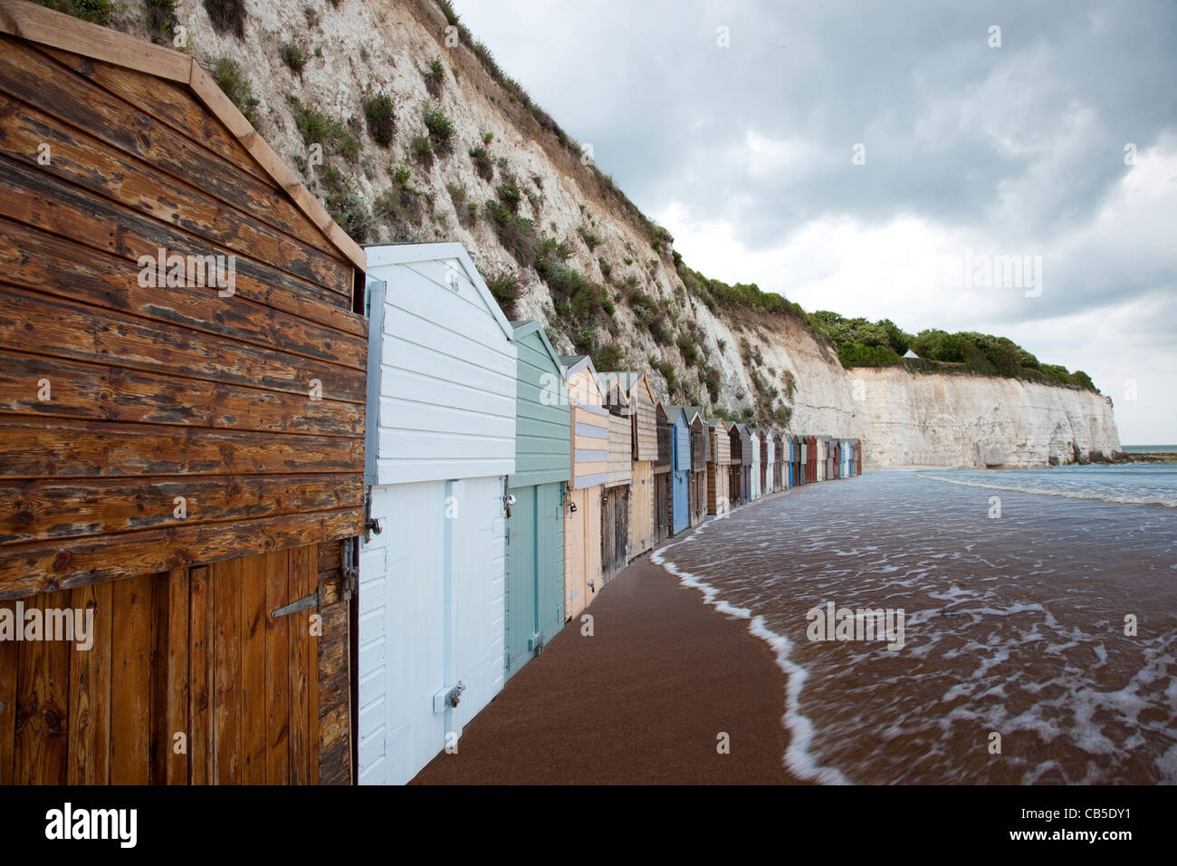 Beach huts in England with the tide approaching them. Stock Photo