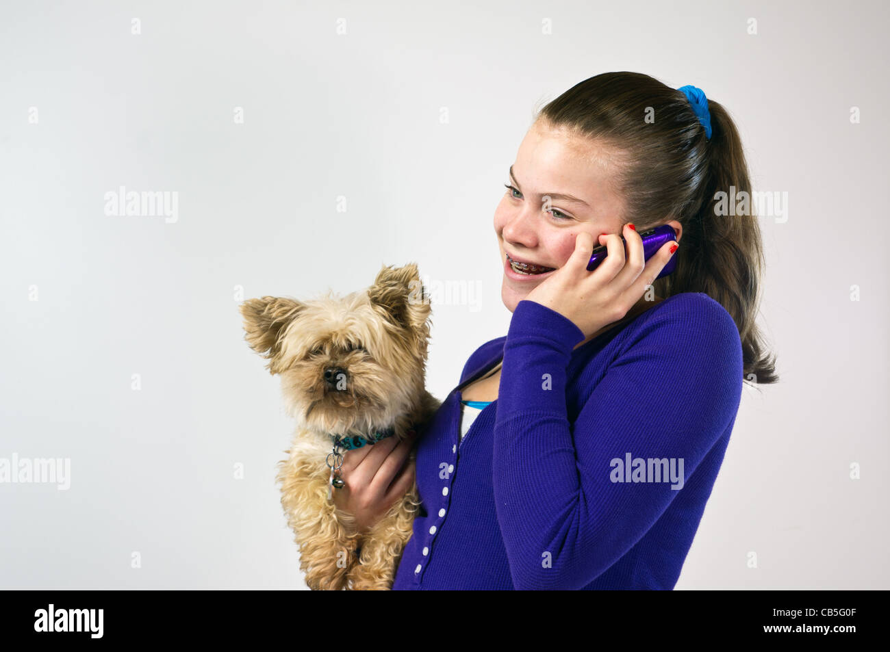 Teen girl talking on the telephone and holding a small dog Stock Photo