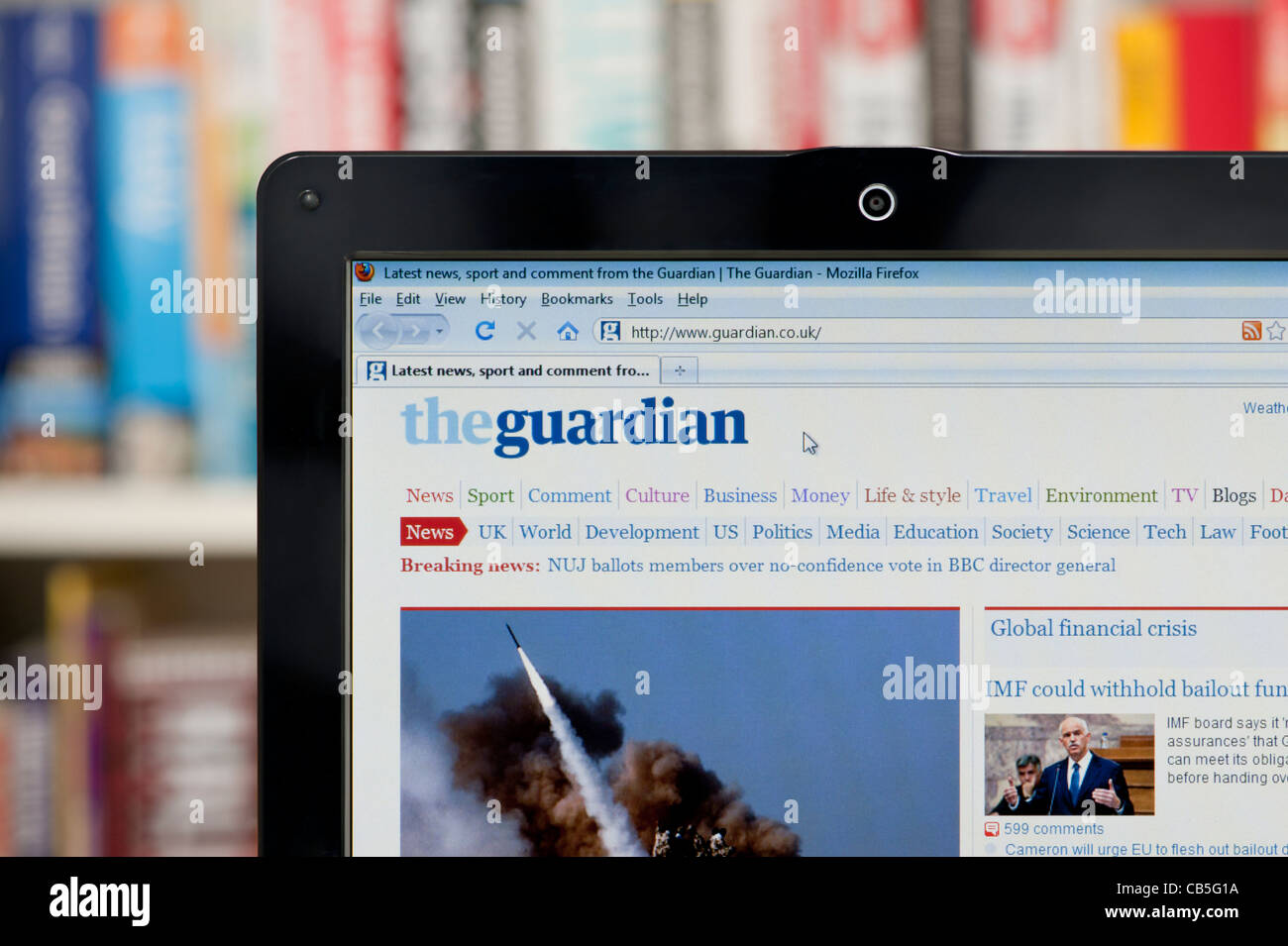 The Guardian newspaper website shot against a bookcase background (Editorial use only: print, TV,e-book and editorial website). Stock Photo