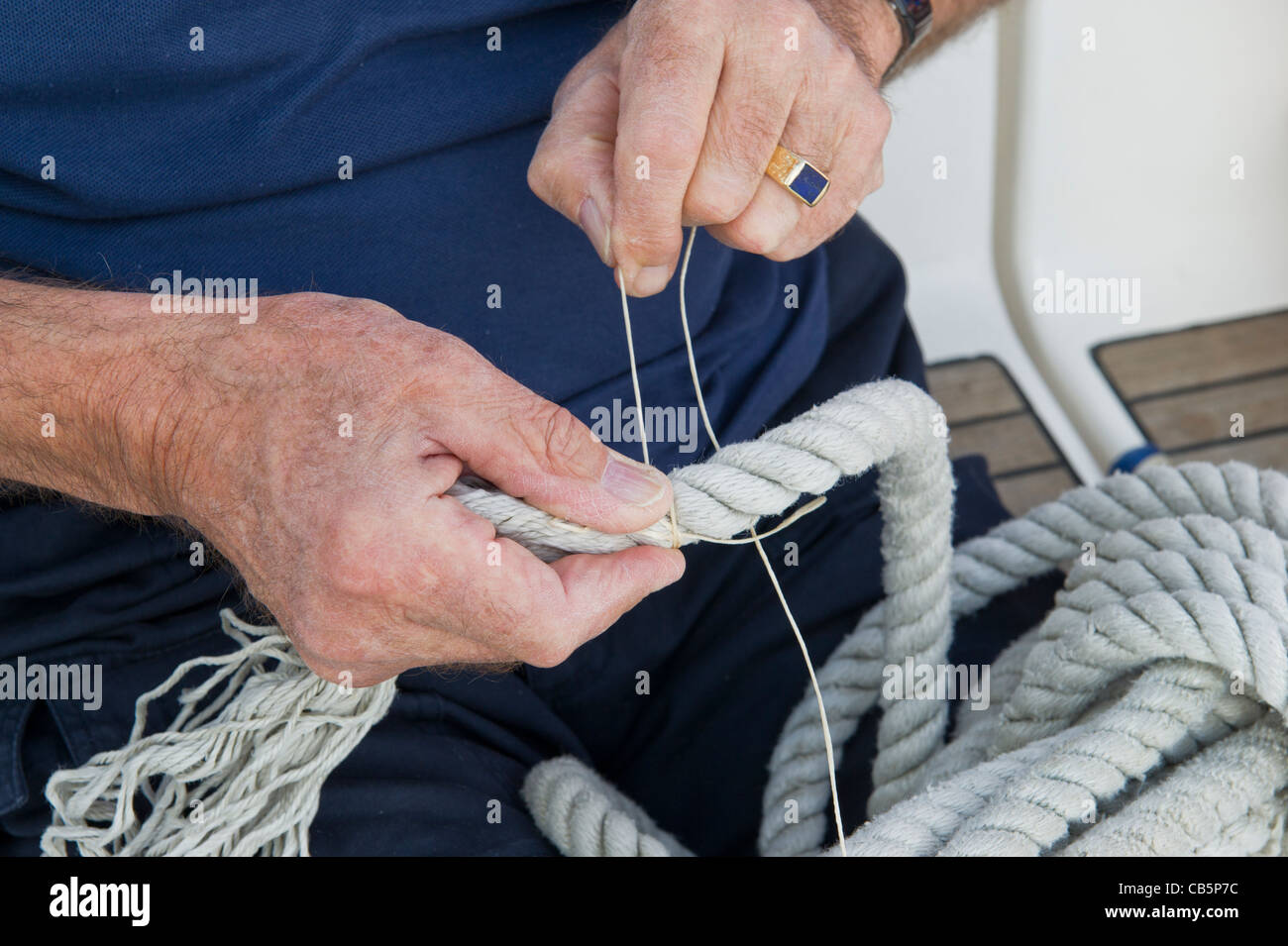 A closeup of a man's hands as he uses whipping twine to repair the