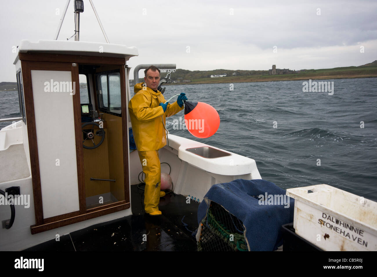 Local fisherman Neil Cameron hauls buoy with creels filled with Velvet and Green Crab between Fionnphort & Iona, Isle of Mull. Stock Photo